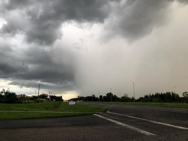 Dark storm cloud with a white wall of rain coming down from it.